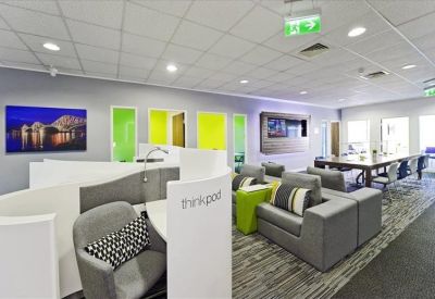 Modern lounge area featuring gray armchairs, privacy pods, and vibrant green wall panels.