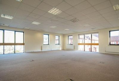 Large open-plan office suite with grey carpeting and bright ceiling lighting.