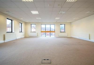 Empty open-plan workspace featuring neutral walls and several windows.