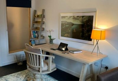Private office workspace featuring a wooden desk, ladder bookshelf, and large wall art.