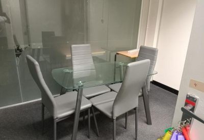 Four-person glass-topped meeting table with sleek grey chairs.