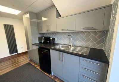 Modern communal kitchen with grey cabinetry and a grey herringbone tile backsplash.