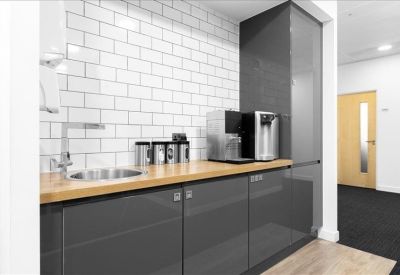Modern kitchen area with charcoal grey cabinetry and white tiled backsplash.