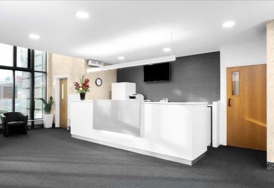 Bright reception area featuring a minimalist white front desk and wooden doors.