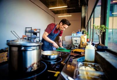 Communal kitchen area with a chef preparing food on a modern stovetop.
