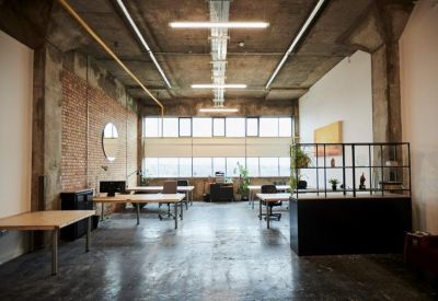 Spacious industrial coworking space with brick walls and exposed concrete ceilings.
