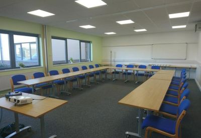 Spacious training room with blue chairs arranged in a U-shape around wooden tables.