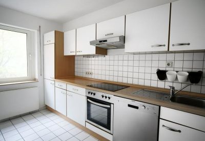 Modern communal kitchen with white cabinetry and integrated appliances.