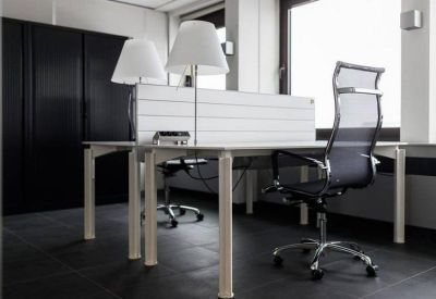 Modern dual-desk workstation with ergonomic mesh chairs and white table lamps.