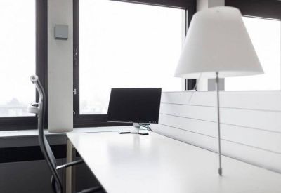Close-up of a clean white desk setup with a computer monitor and lamp.