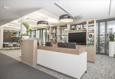 Light-filled reception area with a minimalist wood-topped desk and integrated shelving.