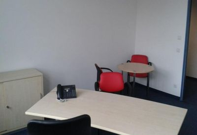 Small meeting area with a circular table and two red accent chairs.