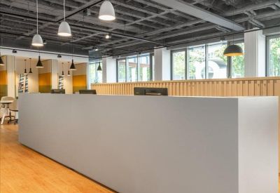 Large minimalist reception desk in an industrial-style space with wood flooring.