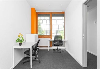 Bright private office with two white desks and an orange feature column.