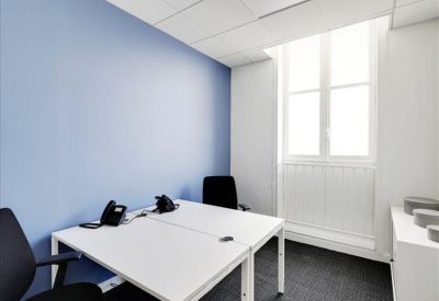 Compact private office with a blue feature wall and white desks.