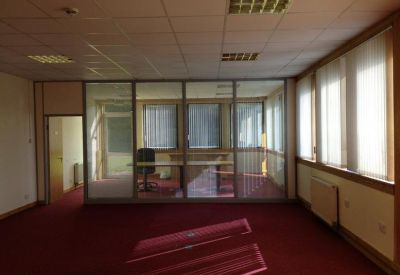 Internal office suite with red carpet, glass partition walls, and natural light from side windows.