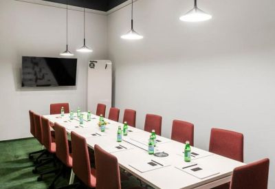 Conference room with red chairs, a long white table, and minimalist pendant lighting.