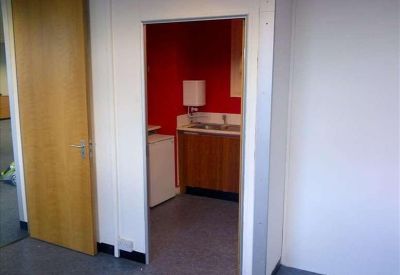 Compact kitchen area with a red accent wall and wooden cabinetry.