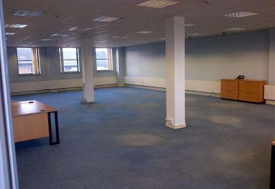 Spacious open-plan office with blue carpeting and white structural pillars.