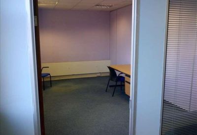 Internal private office suite with lavender walls and a wooden desk.