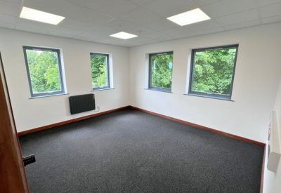 Private office suite with four large windows and dark grey carpeting.