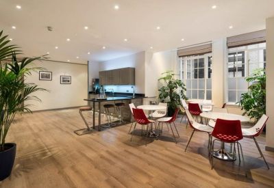 Spacious communal dining area with red chairs, wooden floors, and potted palms.