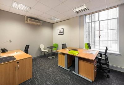 Bright two-person office suite with wooden desks and lime green accent chairs.