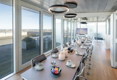 Long boardroom table with modern circular pendant lighting and panoramic city views.