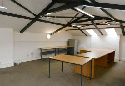 Spacious attic office suite with exposed black steel beams and multiple wooden desks.