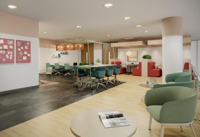 Spacious, modern communal lounge at Godwin Street with teal armchairs, long tables, and vibrant red seating pods.