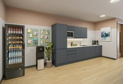 Sleek office kitchen and breakout area featuring dark grey cabinetry and a well-stocked drink refrigerator.