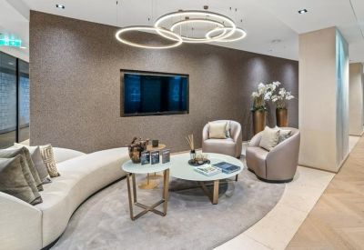Sleek lounge area with a curved white sofa, circular light fixtures, and a wall-mounted TV.