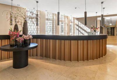 Curved wood-paneled reception desk with elegant floral arrangements and pendant lighting.