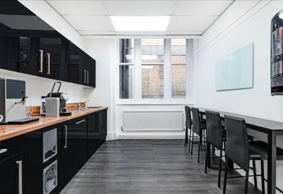 Modern communal kitchen and break area with sleek black cabinetry and breakfast bar seating.