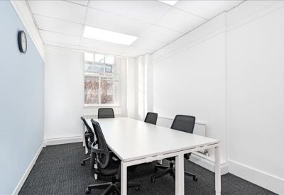 Bright, white meeting room featuring a long table and black ergonomic chairs.
