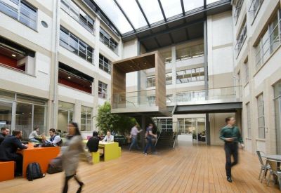 Vibrant indoor atrium with a wooden deck, casual seating, and a modern tree installation.