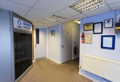 Internal office hallway with white walls, framed certificates, and a radiator.