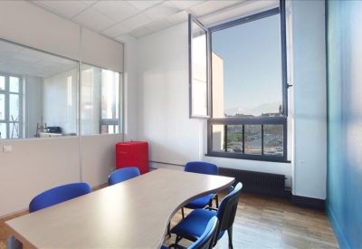 Small meeting room with a curved table, blue chairs, and a large window.