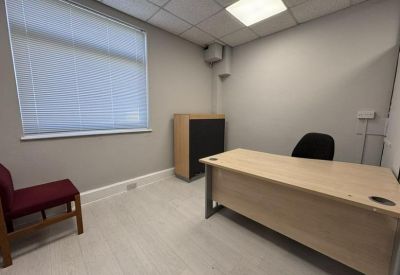 Private office suite with a light wood desk and red visitor chair.