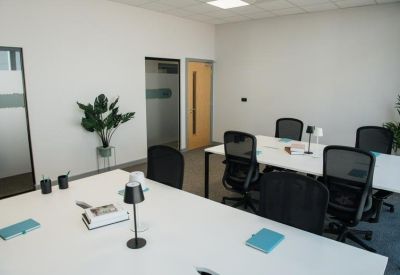 Bright office suite with white desks, ergonomic black chairs, and potted plants.
