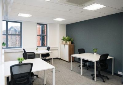 Coworking space featuring a dark grey accent wall and desks with green plants.