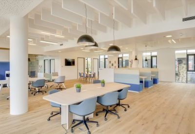 Spacious coworking area with long communal tables and stylish pendant lighting.