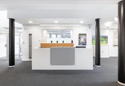 Bright reception area with a minimalist white desk and black architectural pillars.