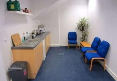 Communal kitchen and breakout area with blue seating and a potted plant.