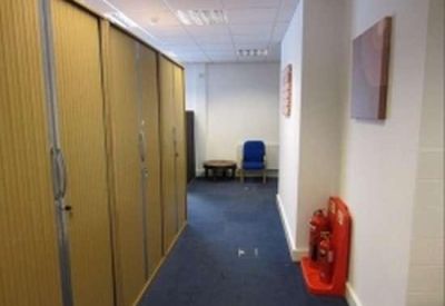 Office corridor featuring a row of tall wooden storage cabinets and a blue chair.