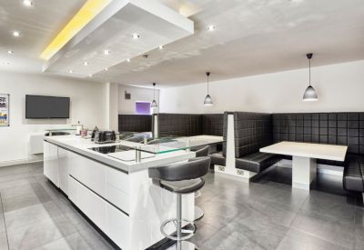 Modern break area with a sleek white kitchen island and black leather booth seating.
