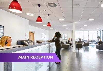 Bright reception area with a long white desk and red pendant lights.