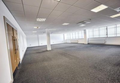 Large empty open-plan office space with grey carpeting and white walls.