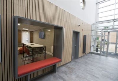 A hallway seating nook with a red cushioned bench built into wood-paneled walls.
