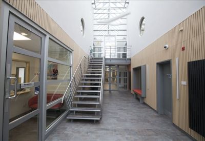 Bright lobby area with a metal staircase, light wood paneling, and a glass skylight.